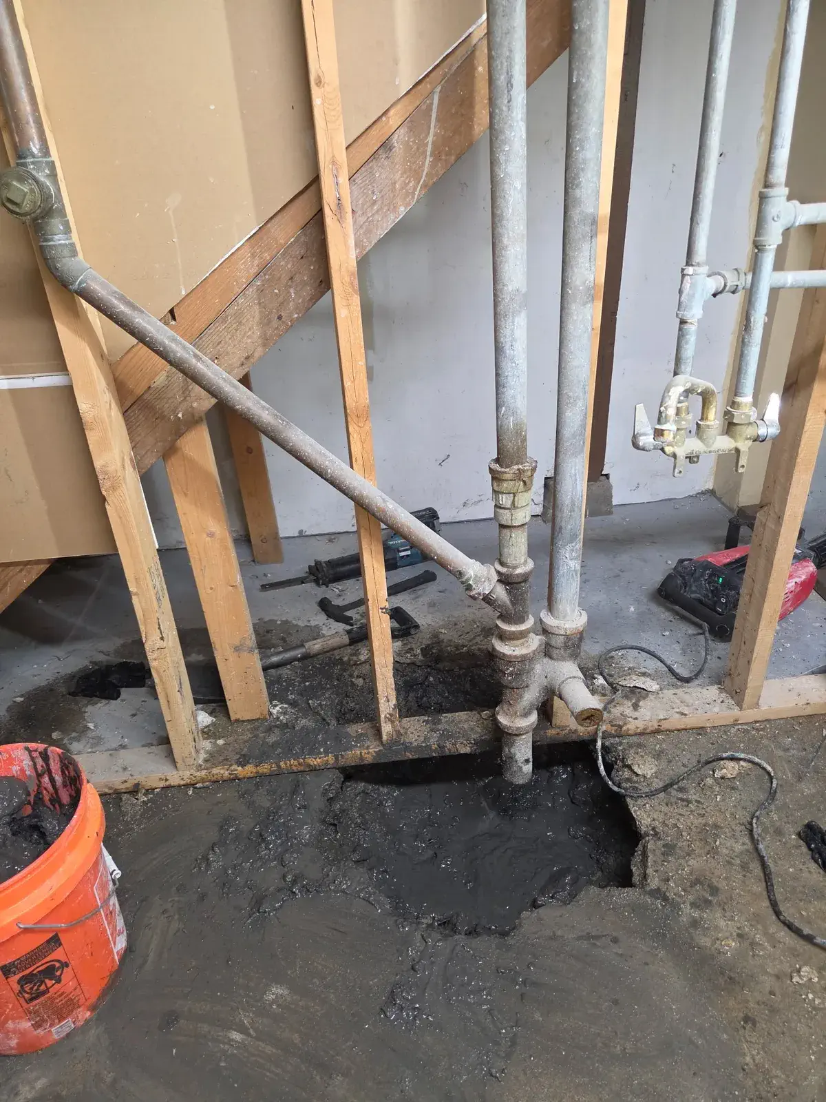 Wood bracing supporting plumbing during a basement sewer repair