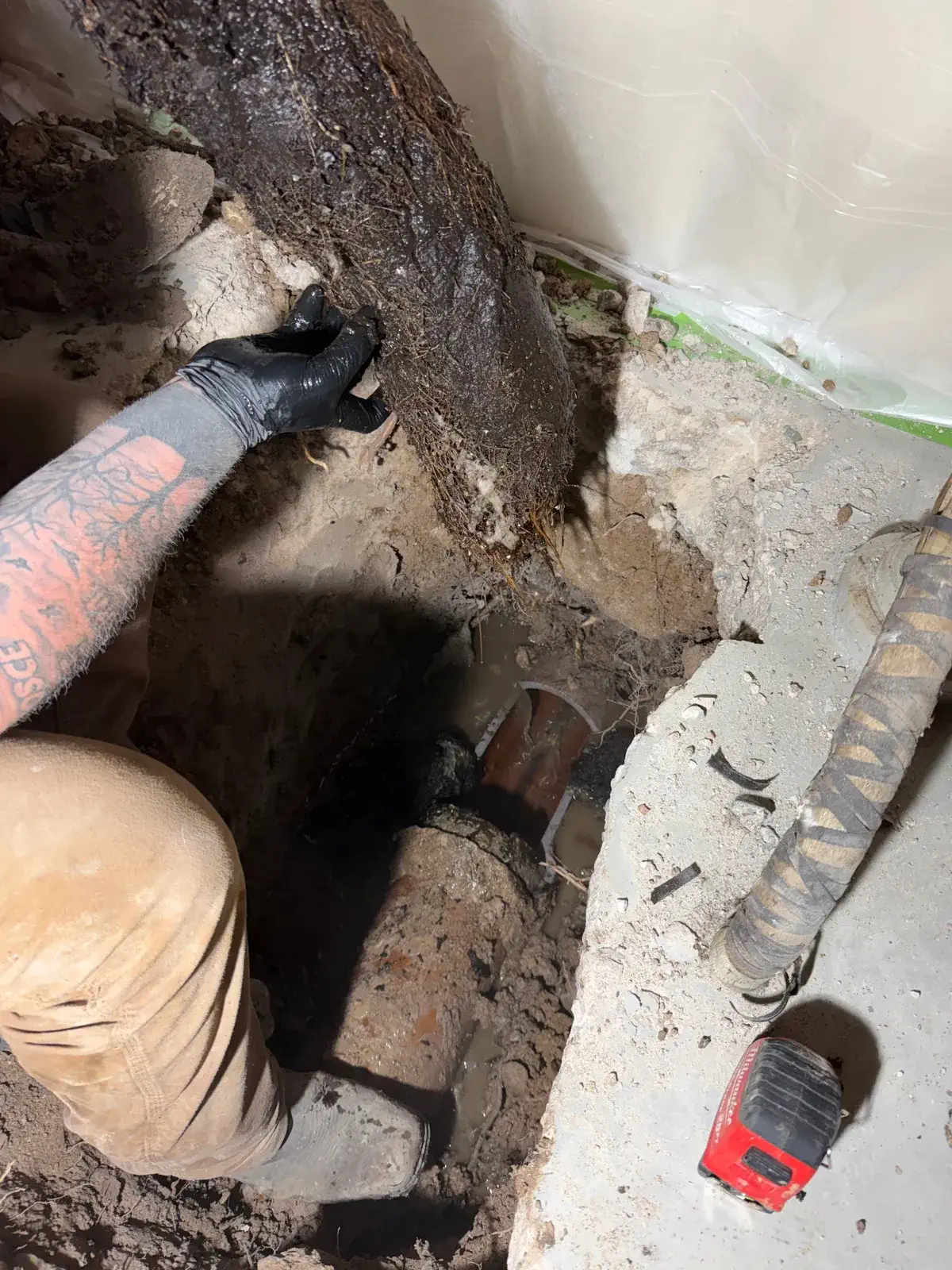 Clearing soil around an old sewer pipe by hand