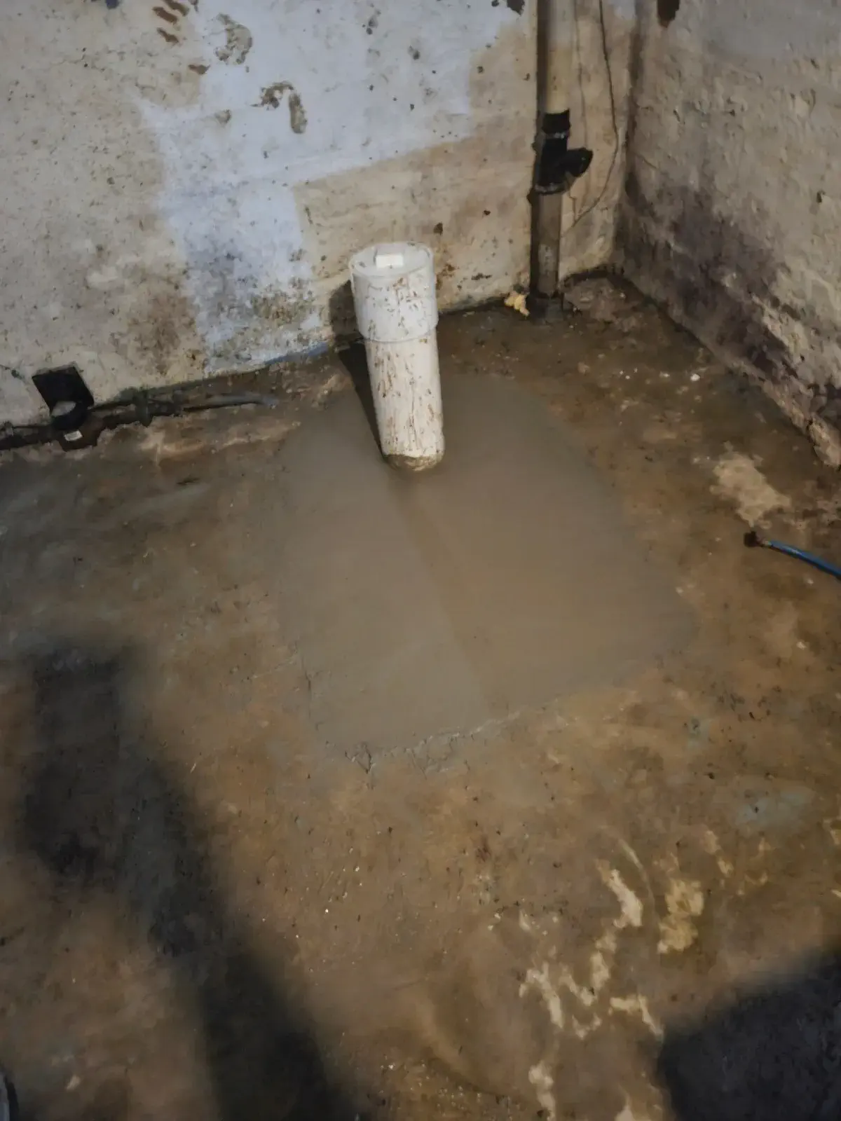Flooded basement floor with standing water around a drain pipe